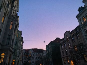 Low angle view of buildings against clear sky at dusk