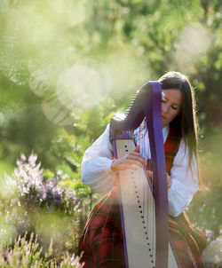 Young woman with umbrella standing in park