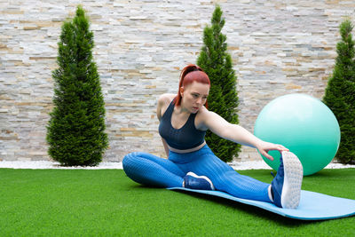 Portrait of young woman exercising on field