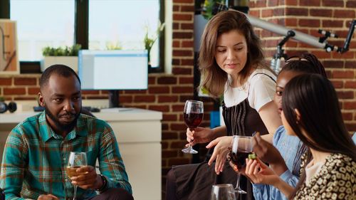 Portrait of smiling friends using mobile phone while sitting in cafe