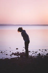 Man standing on beach against sky during sunset