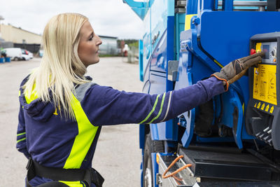 Blond female truck driver standing next to truck