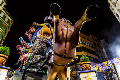 Low angle view of statue in city against sky at night