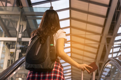 Rear view of women with luggage standing on escalator