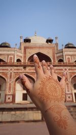 Low angle view of hand against building