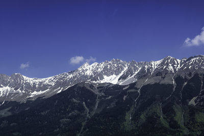 Scenic view of snowcapped mountains against blue sky