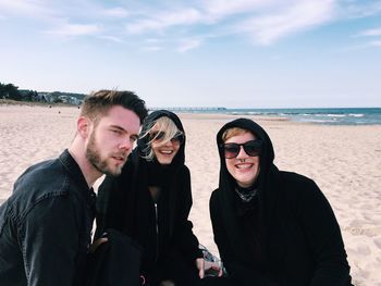 Portrait of friends at beach against sky