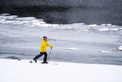 Man skiing by lake during winter