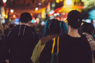 Rear view of people walking on street at night