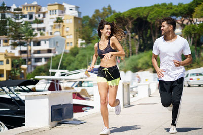 Full length of couple running on footpath