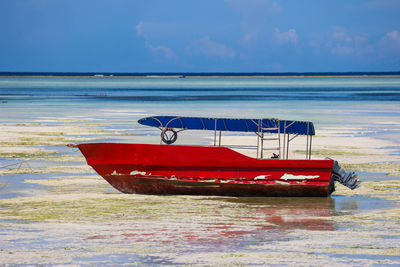 Boat moored on beach against sky