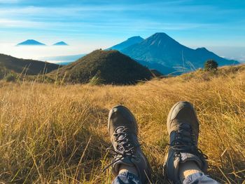 Low section of person on mountain against sky