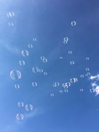 Low angle view of bubbles against blue sky