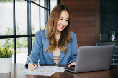 Young businesswoman using laptop at table