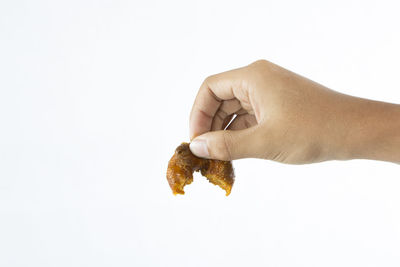 Close-up of hand holding cigarette over white background