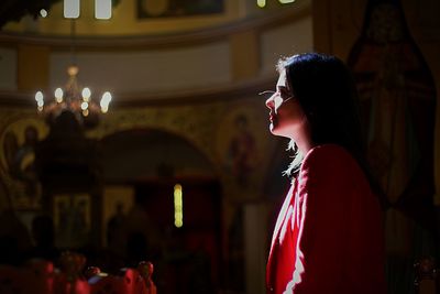 Side view of young woman looking away while praying in church