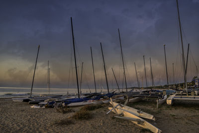 Sailboats moored on beach against sky