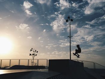 Man standing on railing against sky