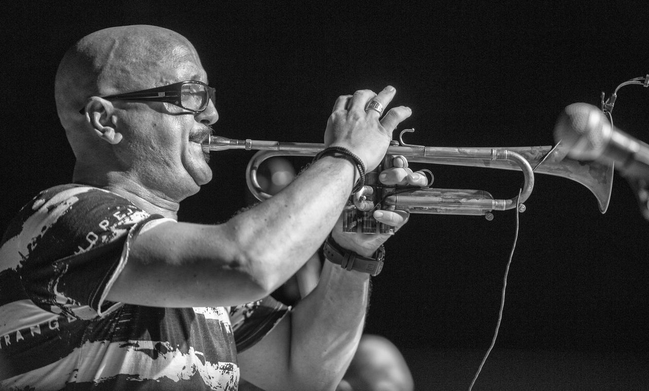 musical instrument, music, arts culture and entertainment, artist, men, musician, one person, black background, playing, mature adult, musical equipment, performance, brass instrument, trumpet, brass, males, holding, mature men, indoors, waist up, skill, completely bald