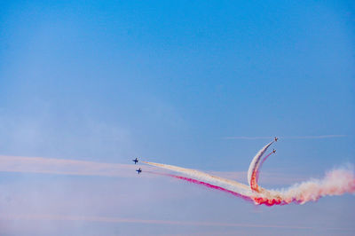 Low angle view of airplane flying against blue sky