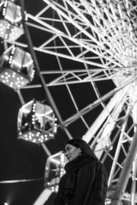 Young beautiful caucasian brunette woman posing by ferris wheel at night. black and white photos 