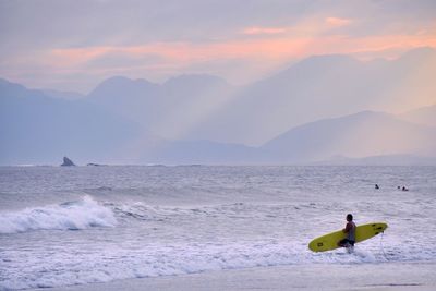 Man surfing in sea against sky