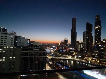 Illuminated buildings in city against sky at night