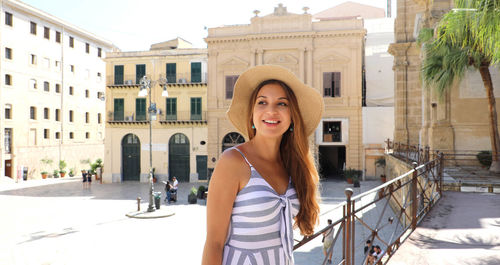 Smiling young woman standing against building