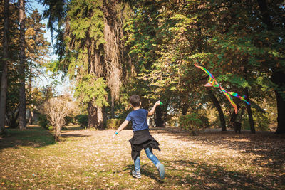 Rear view of boy running on grass amidst trees