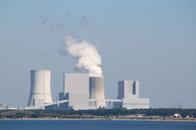 Smoke emitting from factory against clear sky