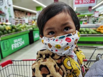 Portrait of cute girl riding cart in supermarket