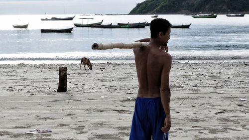 Full length of shirtless man standing on beach