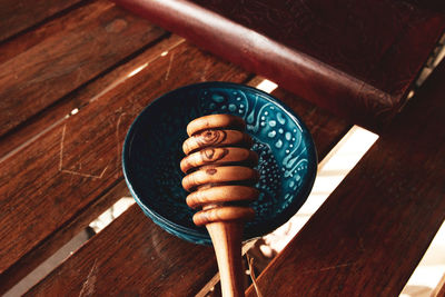 High angle view of honey dipper with bowl on wooden table