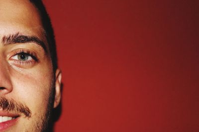 Cropped portrait of young man against red background