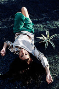 High angle portrait of young woman lying on land in park