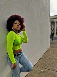 Portrait of young woman standing against wall