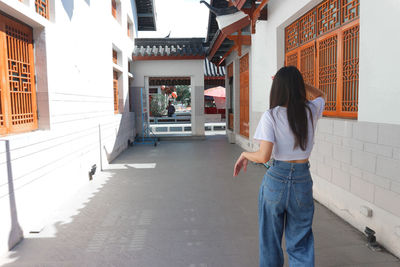 Rear view of woman standing on footpath amidst buildings