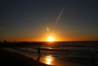 Silhouette man walking on beach against sky during sunset