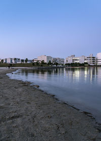 Scenic view of river by buildings against clear blue sky