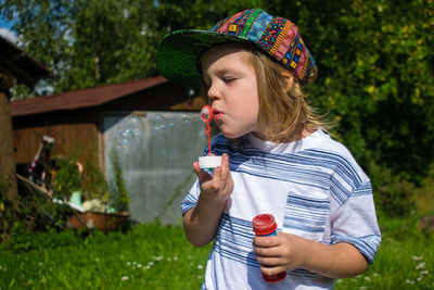 Boy blowing bubbles while standing in yard