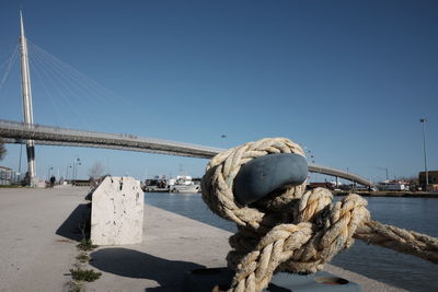 Close-up of rope tied to harbor against clear blue sky