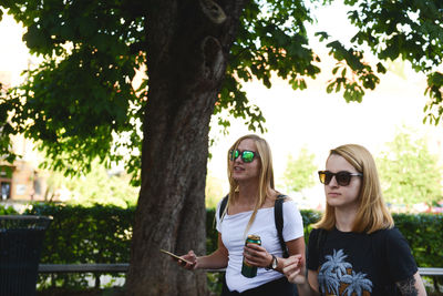 Young woman wearing sunglasses on tree trunk