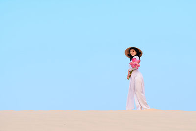 Portrait of woman standing against clear blue sky