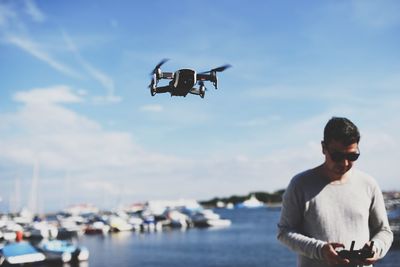 Man flying drone while standing at sea