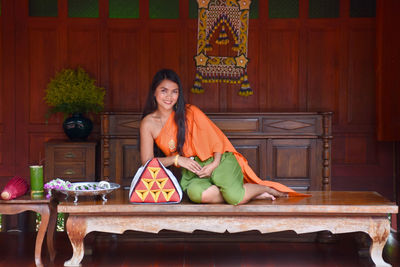 Smiling woman in traditional clothing sitting at temple