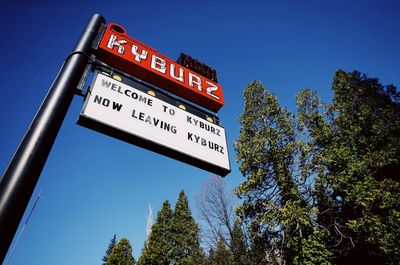 Low angle view of road sign against clear blue sky