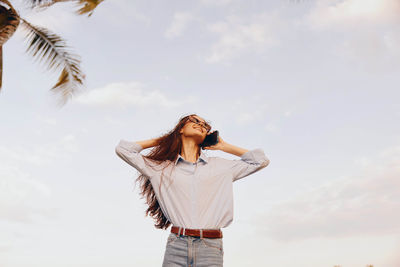 Low angle view of woman standing against sky