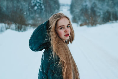 Portrait of young woman standing on snow