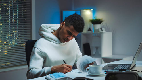 Side view of woman using laptop at home