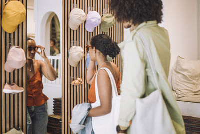 Woman trying sunglasses while standing by man at fashion boutique